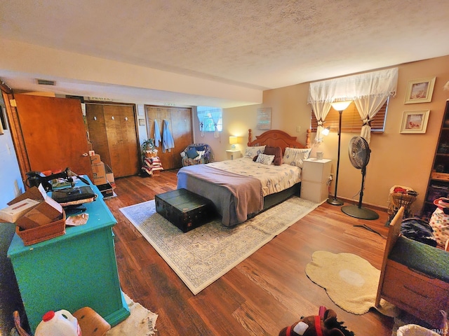 bedroom featuring visible vents, a textured ceiling, and wood finished floors