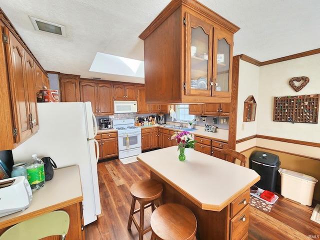 kitchen featuring ornamental molding, white appliances, dark wood-type flooring, brown cabinets, and a skylight