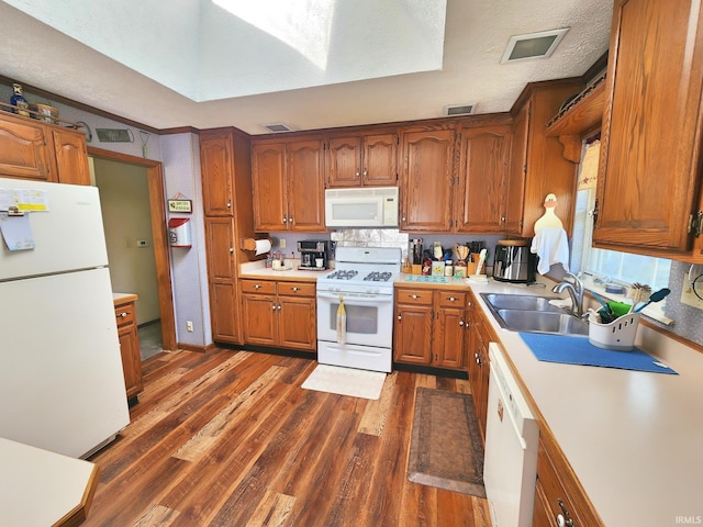 kitchen featuring brown cabinetry, dark wood-style flooring, white appliances, light countertops, and a sink