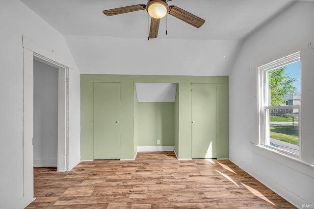 empty room with light wood-style floors, ceiling fan, and vaulted ceiling