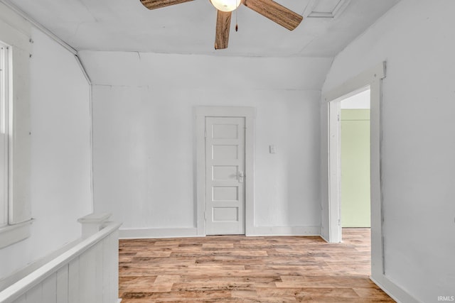 spare room featuring a ceiling fan, light wood-type flooring, and lofted ceiling