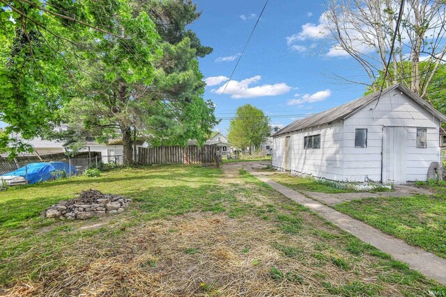 view of yard featuring fence, an outdoor structure, and an outdoor fire pit