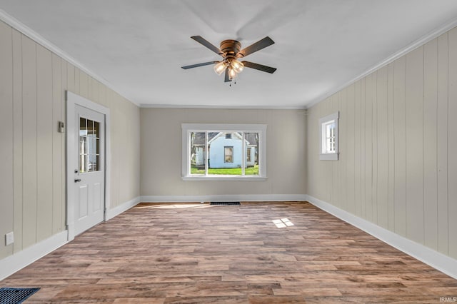unfurnished room with crown molding, a ceiling fan, wood finished floors, and visible vents