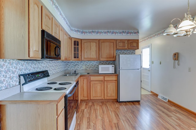 kitchen with visible vents, a sink, light countertops, a notable chandelier, and white appliances