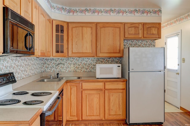 kitchen with white appliances, glass insert cabinets, a sink, and light countertops