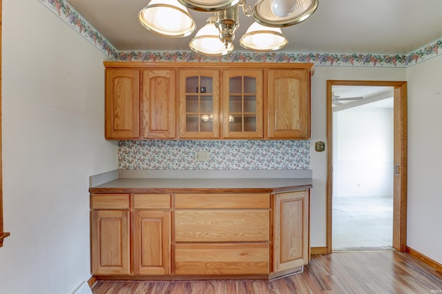 kitchen with glass insert cabinets, baseboards, light countertops, a ceiling fan, and light wood finished floors