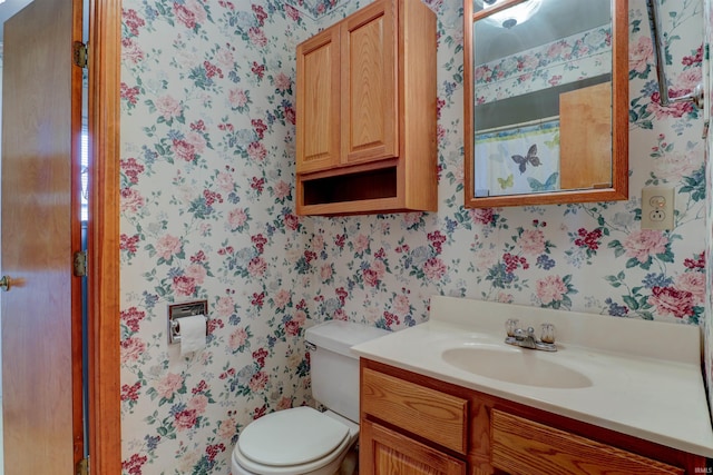 full bath featuring vanity, toilet, and wallpapered walls