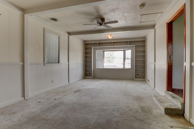 empty room with visible vents, a ceiling fan, carpet floors, and built in shelves