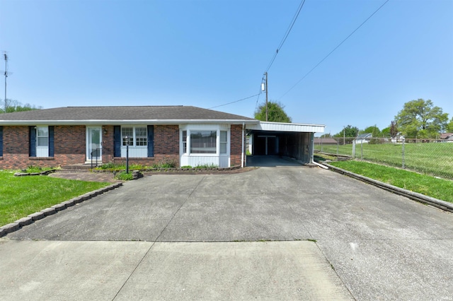 ranch-style home with a front lawn, fence, brick siding, concrete driveway, and a carport