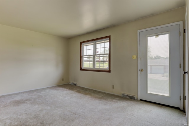 empty room with baseboards, visible vents, and light carpet