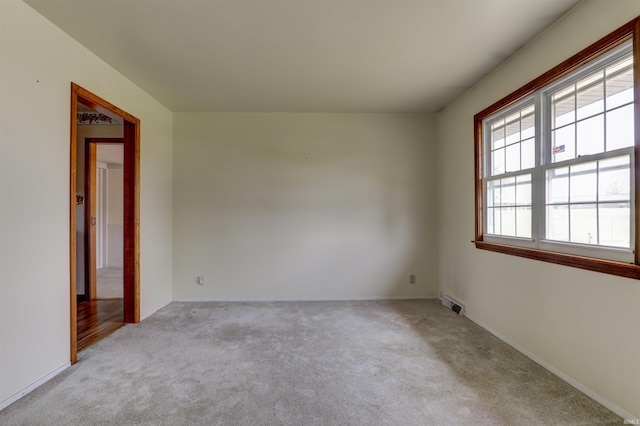 carpeted spare room featuring baseboards and visible vents