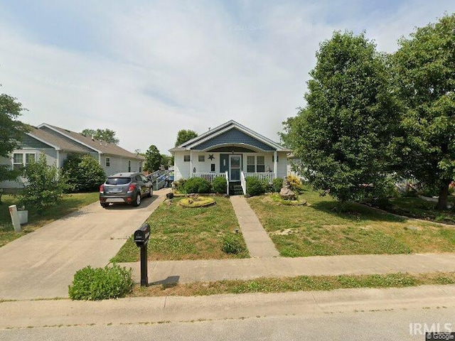 bungalow featuring covered porch, concrete driveway, and a front yard