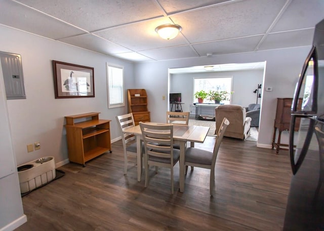 dining space featuring a paneled ceiling, baseboards, wood finished floors, and electric panel