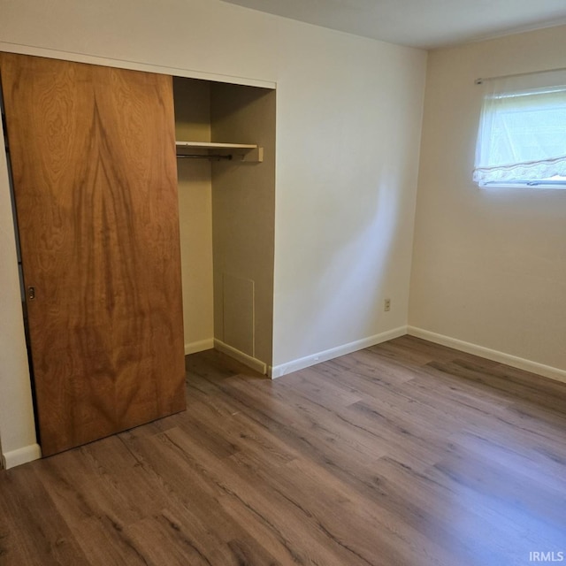 unfurnished bedroom with a closet, baseboards, and wood finished floors