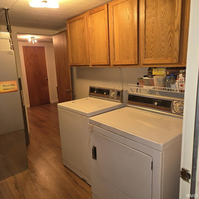 washroom featuring separate washer and dryer, cabinet space, and wood finished floors