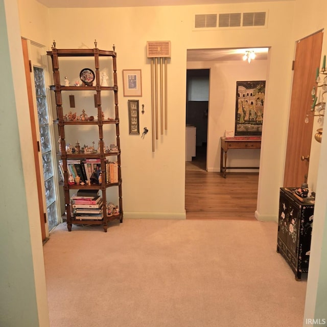 hall with visible vents, baseboards, and carpet floors
