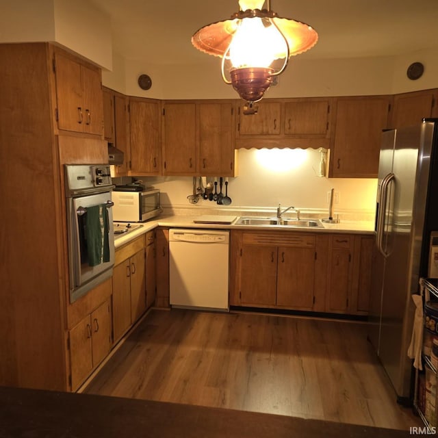 kitchen with light countertops, stainless steel appliances, a sink, and wood finished floors