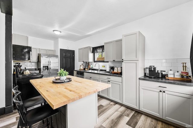 1314 Miner St, South Bend, IN 46617 - kitchen featuring appliances with stainless steel finishes, a kitchen breakfast bar, backsplash, and butcher block countertops
