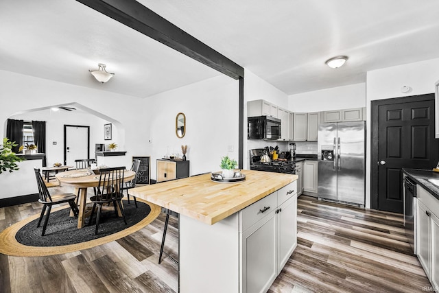 1314 Miner St, South Bend, IN 46617 - kitchen featuring a kitchen breakfast bar, wood counters, arched walkways, stainless steel appliances, and wood finished floors