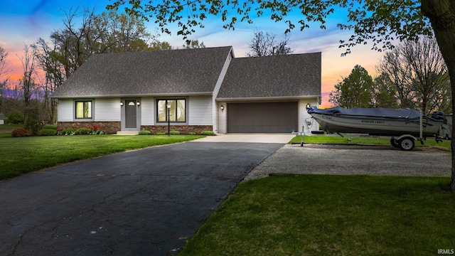 view of front facade featuring a garage, driveway, roof with shingles, and a front yard