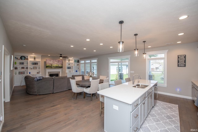 kitchen with a ceiling fan, wood finished floors, a fireplace, recessed lighting, and a sink