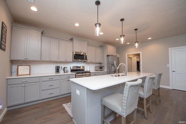 kitchen with gray cabinetry, appliances with stainless steel finishes, a sink, and an island with sink