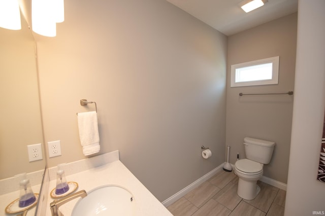 bathroom featuring baseboards, toilet, and vanity