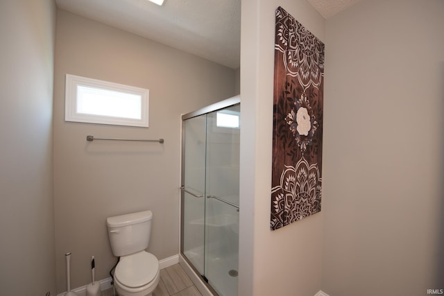 bathroom featuring baseboards, a stall shower, and toilet