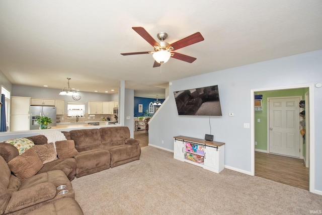 carpeted living room featuring baseboards, recessed lighting, a sink, and ceiling fan with notable chandelier