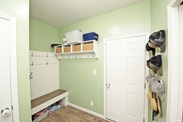 mudroom with a textured ceiling, baseboards, visible vents, and wood finished floors