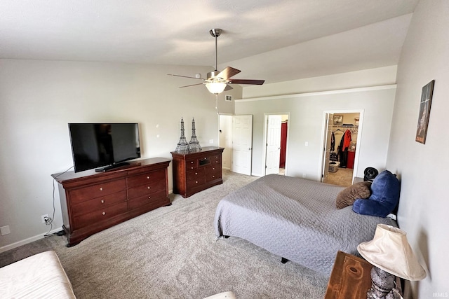 bedroom featuring light colored carpet, a walk in closet, a ceiling fan, baseboards, and lofted ceiling