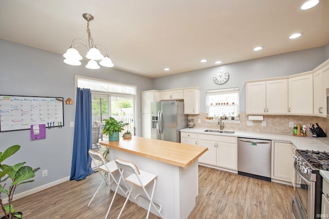 kitchen featuring backsplash, appliances with stainless steel finishes, a sink, and light wood finished floors