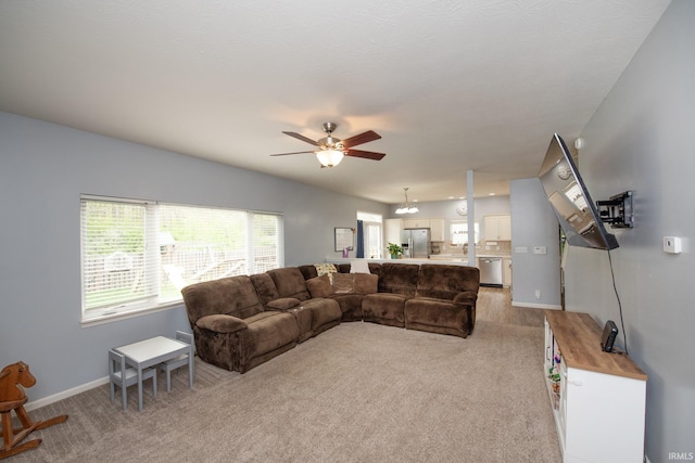 living area with baseboards, a ceiling fan, and light carpet