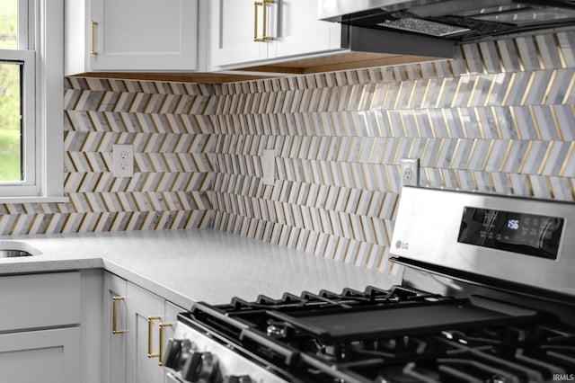 interior space with decorative backsplash, extractor fan, white cabinets, and gas range