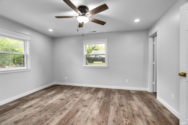 empty room featuring ceiling fan, visible vents, plenty of natural light, and wood finished floors