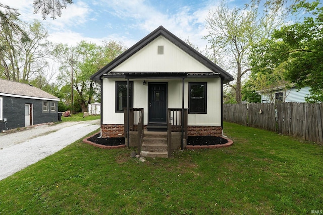 view of front of property featuring brick siding, fence, and a front lawn