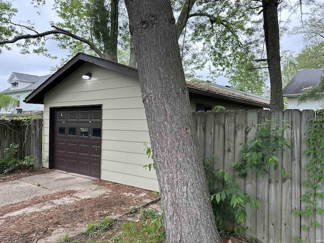 view of side of property with an outdoor structure, fence, driveway, and a garage
