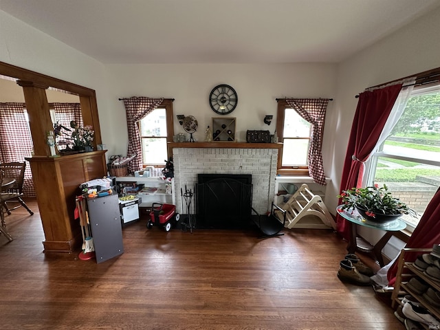 living area with a brick fireplace, a healthy amount of sunlight, and wood finished floors