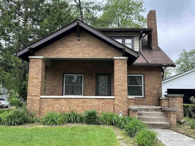 bungalow with a chimney, a front lawn, and brick siding