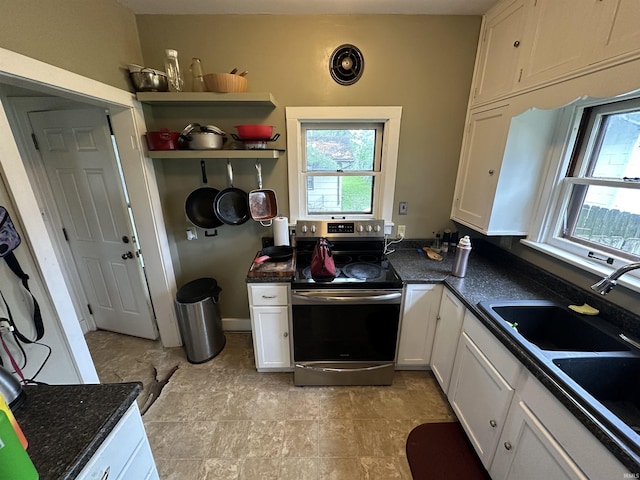 kitchen featuring open shelves, stainless steel range with electric stovetop, white cabinets, a sink, and dark stone countertops