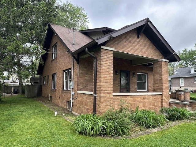 view of home's exterior featuring brick siding, a lawn, and fence