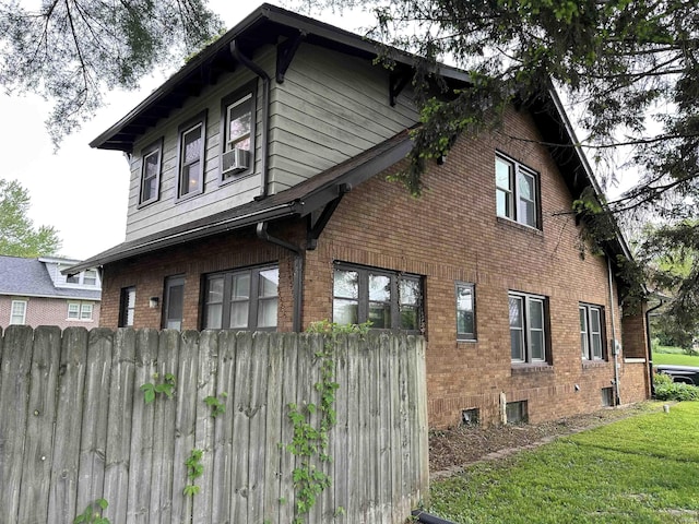 view of home's exterior featuring a lawn, brick siding, fence, and cooling unit
