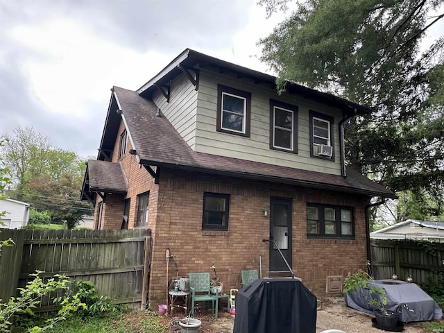 back of property with fence, a shingled roof, and brick siding