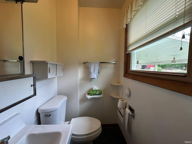half bath featuring baseboards, a sink, and toilet