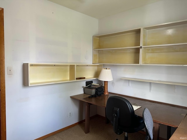 unfurnished office featuring carpet flooring, baseboards, and built in study area