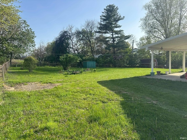 view of yard featuring fence, an outdoor structure, a shed, and a patio