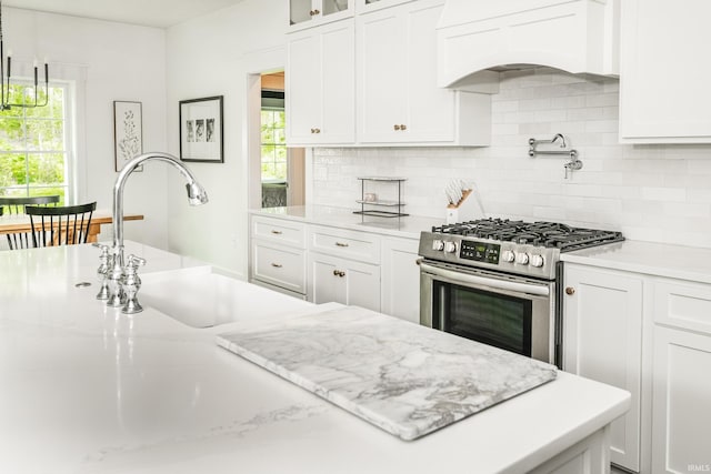 1284 E Zinnia Dr, Bloomington, IN 47401 - kitchen with a healthy amount of sunlight, backsplash, stainless steel gas range oven, a sink, and white cabinets