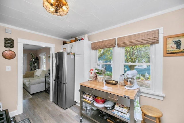 kitchen featuring crown molding, white cabinets, freestanding refrigerator, light wood-type flooring, and visible vents