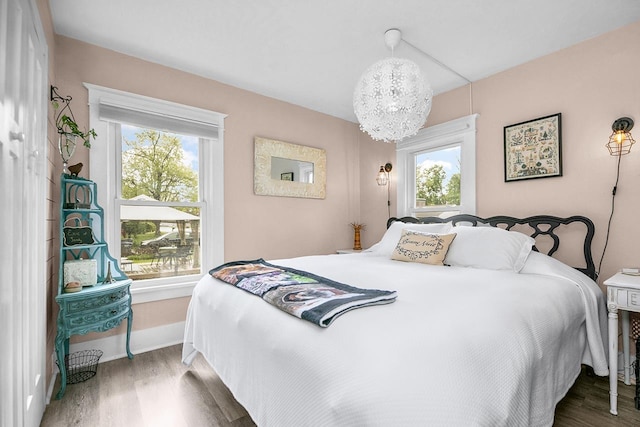 bedroom with baseboards, an inviting chandelier, and wood finished floors