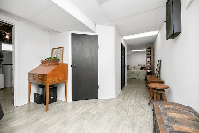hallway with baseboards, a drop ceiling, and wood finished floors